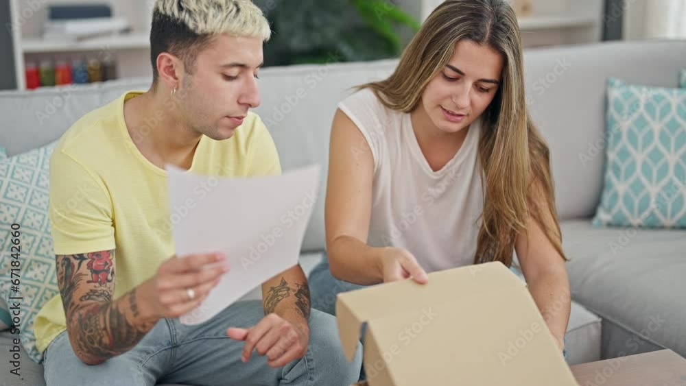 Beautiful couple reading document unpacking cardboard box at home Beautiful couple reading document unpacking cardboard box at home