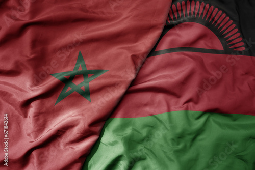 big waving national colorful flag of morocco and national flag of malawi .