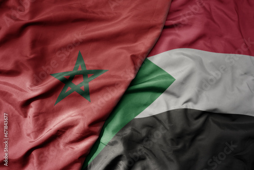 big waving national colorful flag of morocco and national flag of sudan .