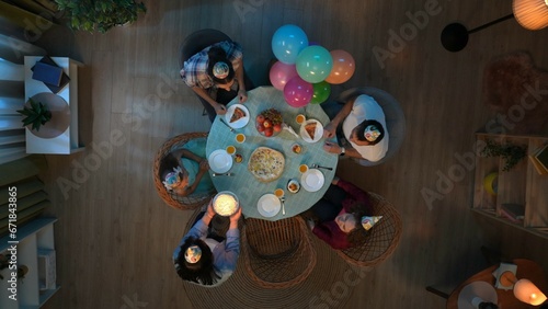 Top view of table with party food and drinks. Family with friends celebrating little girl birthday, mom brings cake with candles.