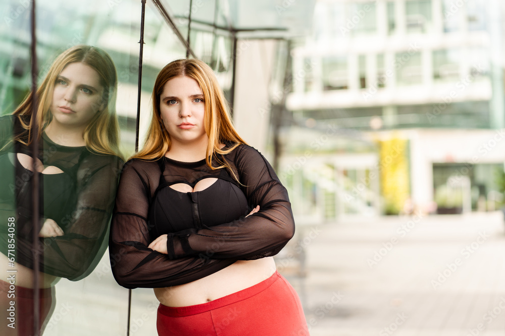 Pretty overweight woman in sportswear posing outdoors and looking at camera. Body positive, plus size, motivation