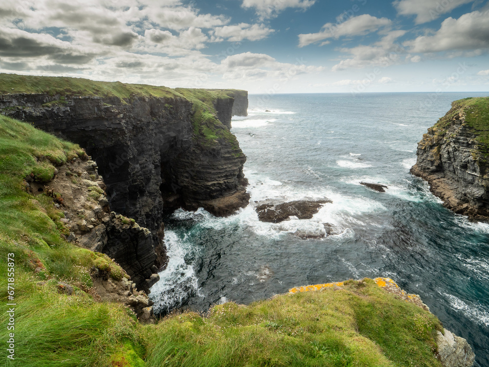 Stunning coastline of Ireland in Kilkee area. Low cloudy sky, warm sunny day. Travel, tourism and sightseeing concept. Irish landscape and coastline. Rough terrain and ocean surface.