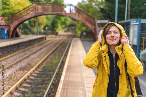 Portrait of young beautiful woman  traveler  wearing yellow raincoat outside in autumn scenery waiting for a metro train