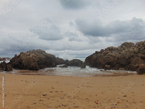 Olas llegando a la playa abriéndose paso entre las rocas un día nublado en una playa de Cantabria 