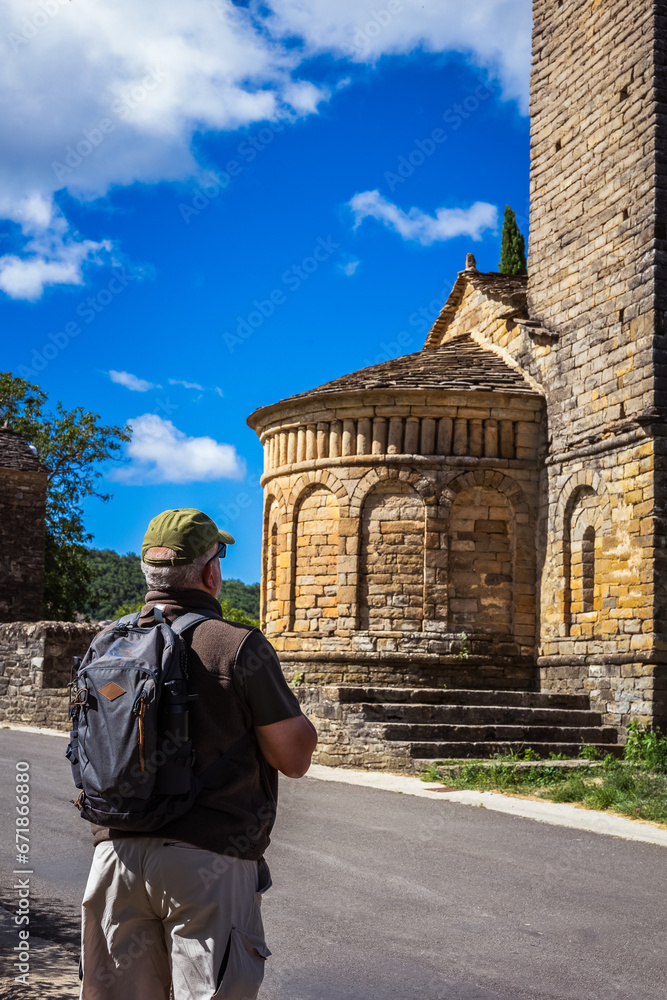 lone male hiker walking on the road, taking the opportunity to do some sightseeing by visiting an ancient Romanesque monument along the way