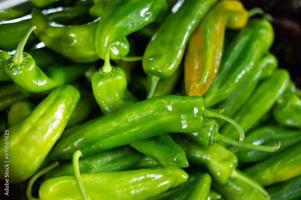 Bunch of fresh green bell peppers lie on counter in vegetable shop