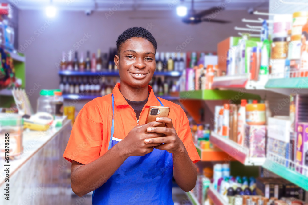 handsome young African supermarket sales attendant holding cell phone