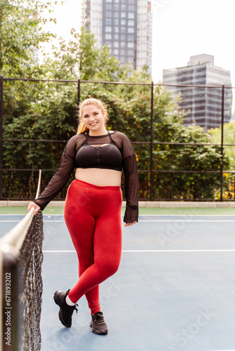 Smiling woman with plus size body relaxing after workout session outdoors. Plus size model, motivation, training