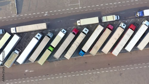 Aerial Shot of Truck with Attached Semi Trailer Leaving Industrial Warehouse/ Storage Building/ Loading Area where Many Trucks Are Loading/ Unloading Merchandise. Shot on Phantom 4K UHD Camera. photo