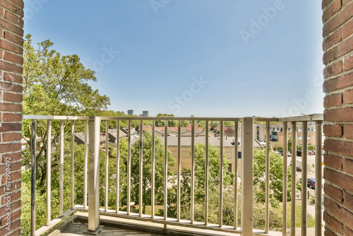 a balcony with trees and houses in the background, taken from an apartment window looking out at a blue sky