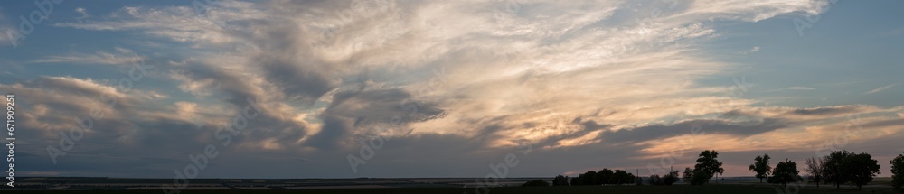 A landscape with an enchanting sunset. Panorama. Tragic gloomy sky. The last flashes of the sun on the storm clouds.