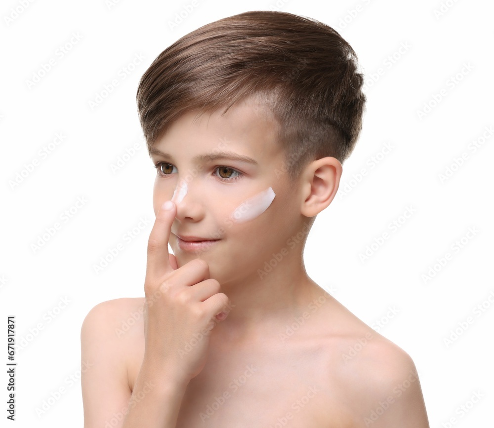 Smiling boy applying sun protection cream onto his face against white background Smiling boy applying sun protection cream onto his face against white background
