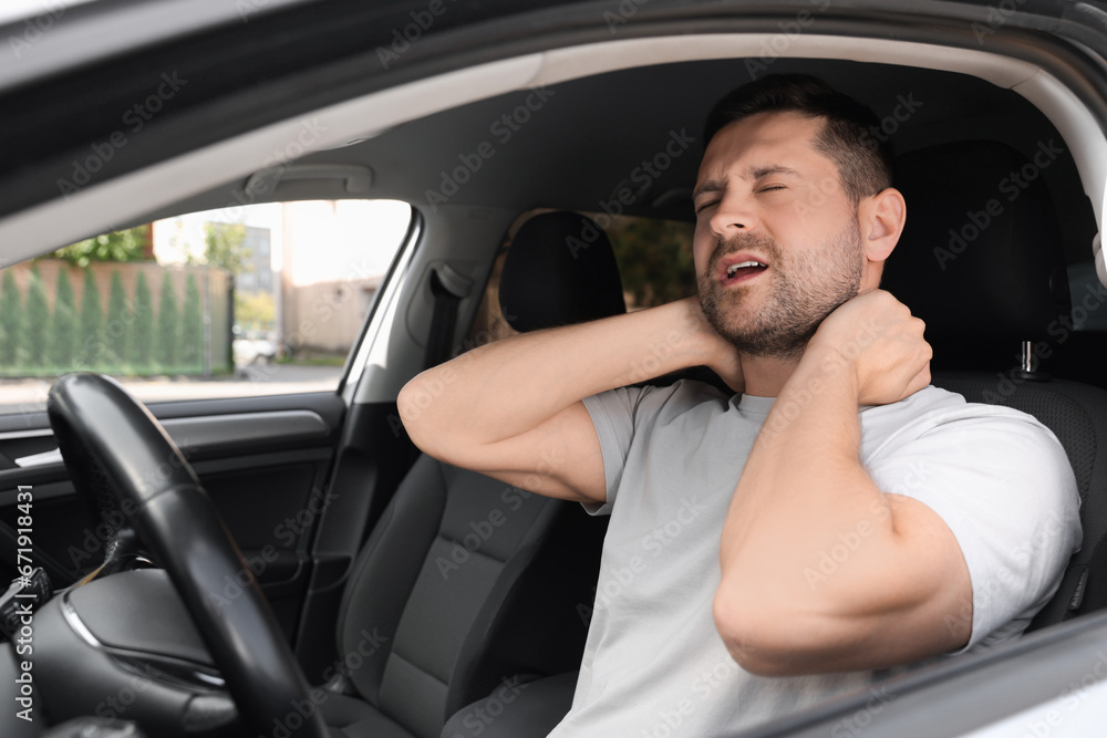Man suffering from neck pain in car Man suffering from neck pain in car