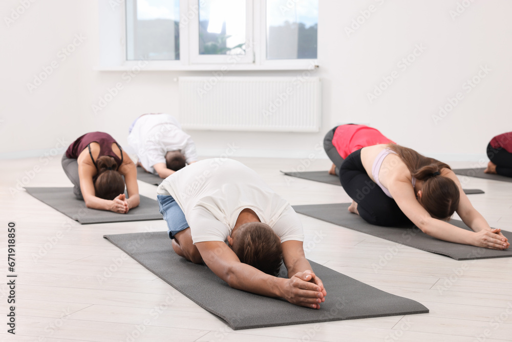 Naklejka premium Group of people practicing yoga on mats indoors