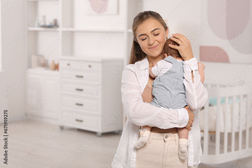 Mother holding her cute newborn baby in child's room, space for text Mother holding her cute newborn baby in child's room, space for text