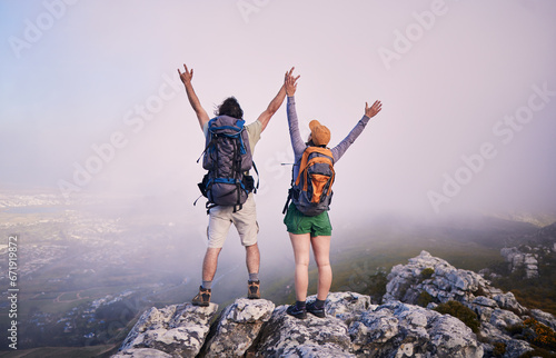 Mountain, hiking achievement and couple from back on adventure in nature, landscape and travel. Outdoor trekking, man with woman on cliff and relax in view of clouds, natural journey and winning.