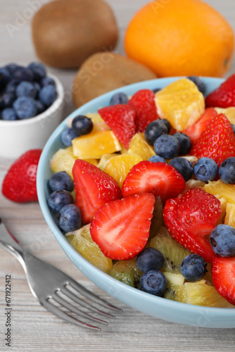 Delicious fresh fruit salad in bowl served on wooden table  closeup