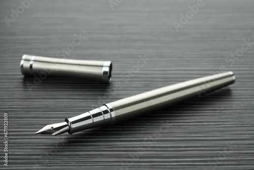 Stylish silver fountain pen on black wooden table, closeup