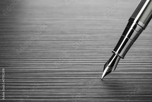 Stylish silver fountain pen on black wooden table, closeup. Space for text