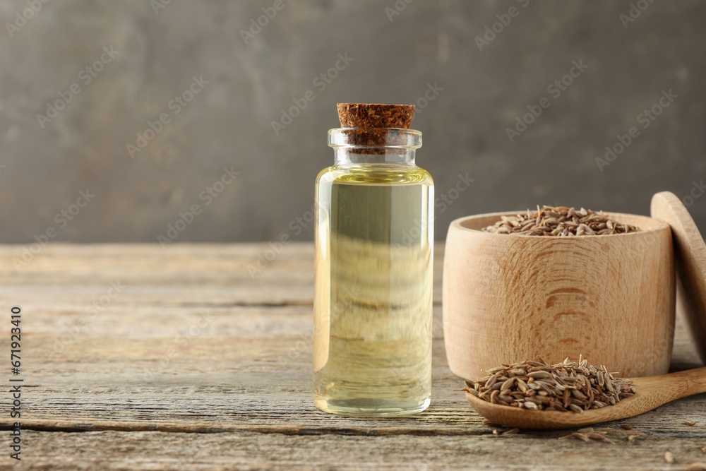 Caraway (Persian cumin) seeds and essential oil on wooden table, space for text Caraway (Persian cumin) seeds and essential oil on wooden table, space for text