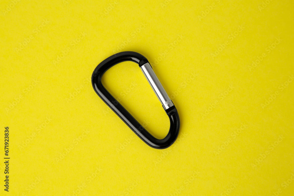 One black carabiner on yellow background, top view One black carabiner on yellow background, top view