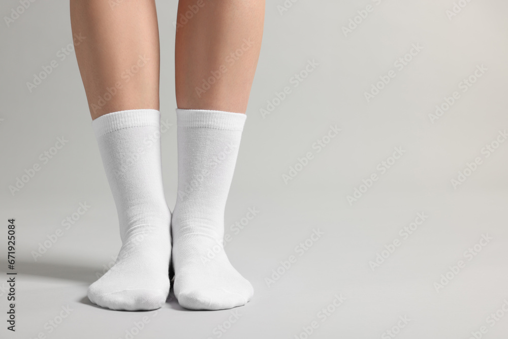 Woman in stylish white socks on light grey background, closeup. Space for text Woman in stylish white socks on light grey background, closeup. Space for text