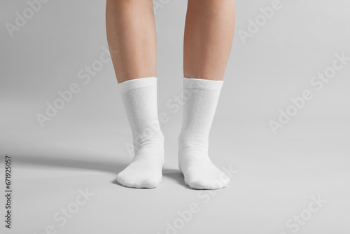 Woman in stylish white socks on light grey background, closeup