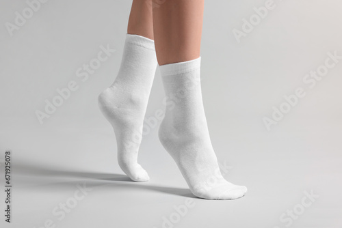Fototapeta Naklejka Na Ścianę i Meble -  Woman in stylish white socks on light grey background, closeup