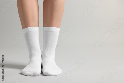 Woman in stylish white socks on light grey background, closeup. Space for text