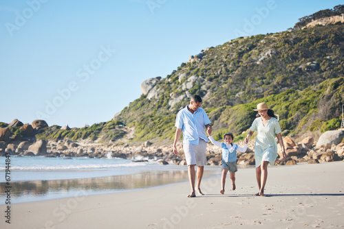 Beach, mother and father holding hands with a child for fun, family adventure and play on holiday. A happy woman, man and young kid walking on sand for vacation at ocean, nature or outdoor in summer © Azeemud/peopleimages.com