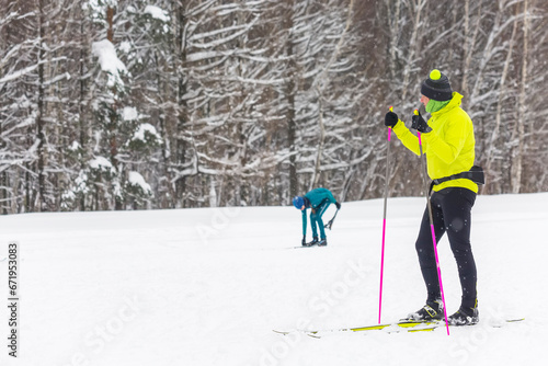 A guy on cross-country skis, dressed in a yellow electric jacket on the background of a snow-covered forest photo