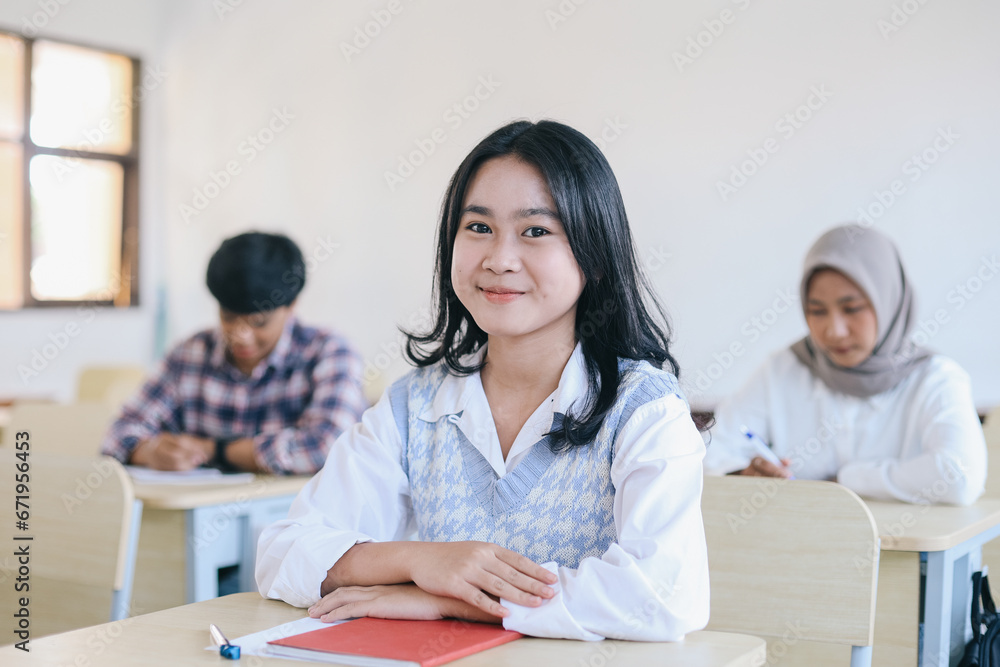 Portrait of smiling asian female student sitting at desk in classroom at university Portrait of smiling asian female student sitting at desk in classroom at university