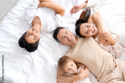 Little children with their parents lying on bed, top view