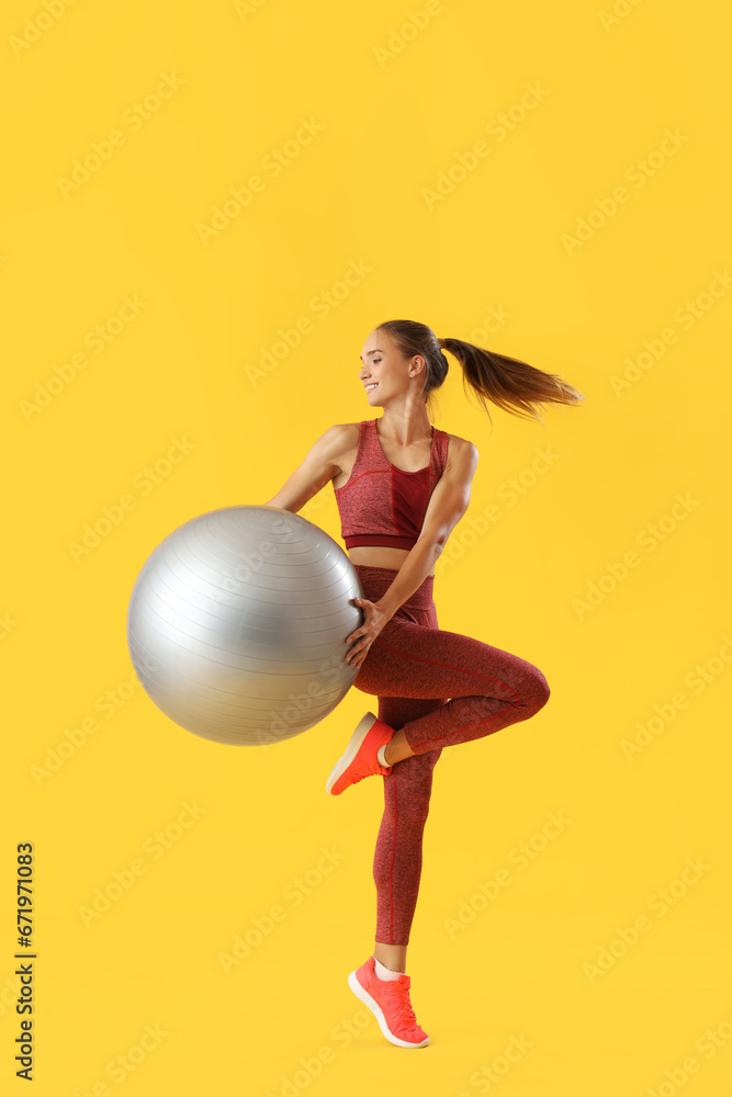 Sporty young woman training with fitball on yellow background Sporty young woman training with fitball on yellow background