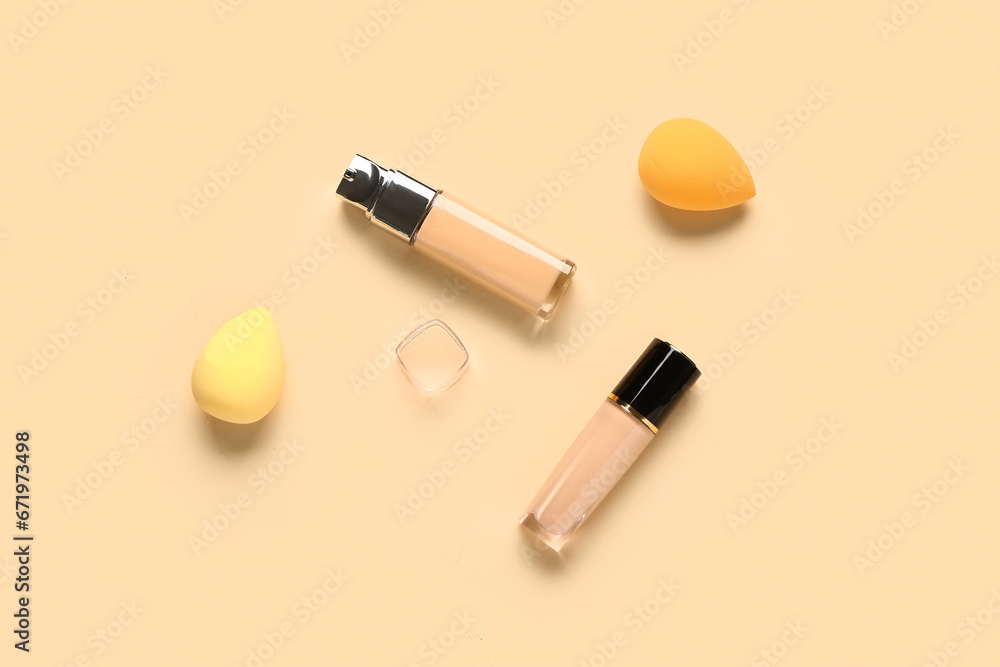 Bottles of makeup foundation with sponges on beige background Bottles of makeup foundation with sponges on beige background