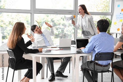 Young businesswoman with megaphone shouting at colleagues in office photo