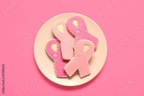 Plate with cookies in shape of pink ribbon on color background. Breast cancer awareness concept