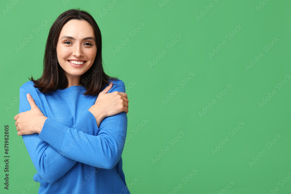 Young woman hugging herself on green background Young woman hugging herself on green background
