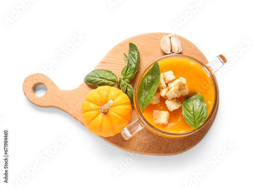 Glass pot of delicious pumpkin cream soup with croutons  basil and garlic on white background