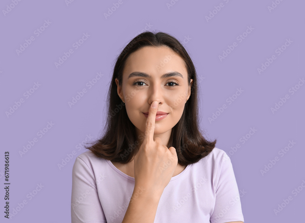 Young woman touching her nose on lilac background, closeup Young woman touching her nose on lilac background, closeup