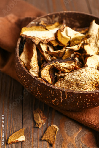 Bowl with tasty dried mushrooms on wooden background, closeup