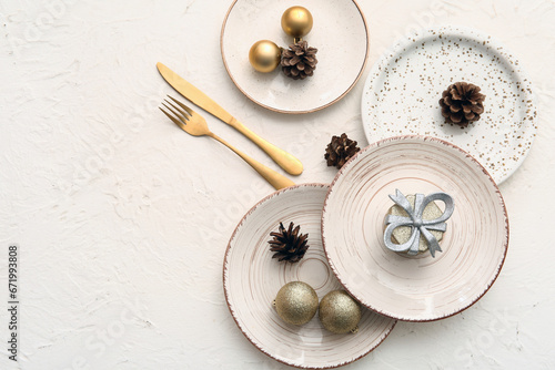 Beautiful table setting with Christmas balls, cones and gift box on white background