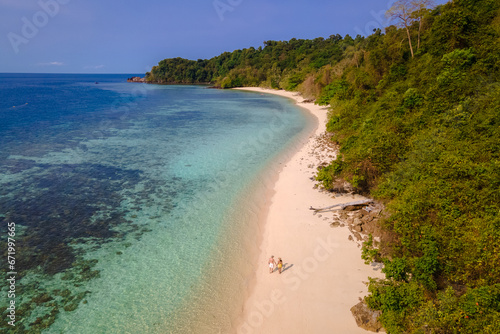 a couple of men and women sitting at the beach of Koh Kradan island in Thailand