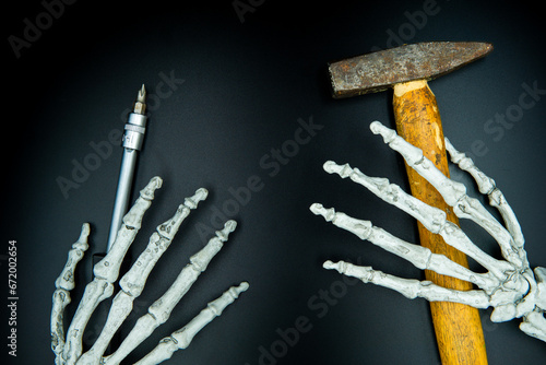 death lending a helping hand skeleton hands holding a hammer and screwdriver photo