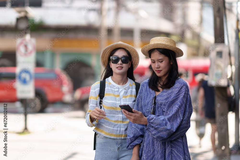 Travellers two young female tourists, Asian backpackers travel from place to place with cell phones to search for information on tourist attractions on a relaxing vacation. Lifestyle, Holiday concept
