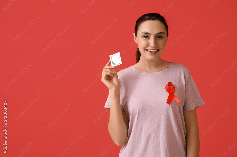 Young woman with condom and red ribbon on color background. AID awareness concept Young woman with condom and red ribbon on color background. AID awareness concept