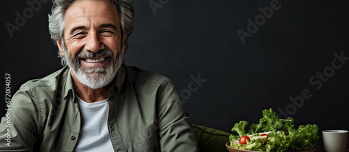 An elderly gentleman with a senior lifestyle experiences joy while indulging in a nutritious meal consisting of a refreshing salad and a glass of freshly squeezed orange juice while comforta photo