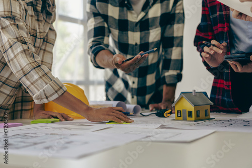 Engineer and businessman discussing construction project in office, team of engineers reviewing construction blueprints on new project with engineering tools at table in office