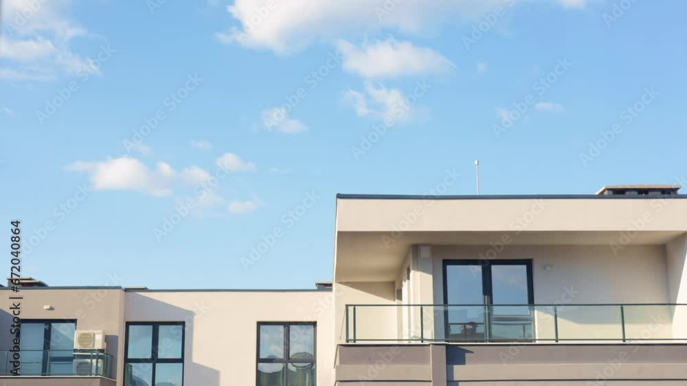 Timelaps of clouds passing over a modern apartment building, reflecting in it's windows. Shot on a bright cunny day with a beautiful blue sky