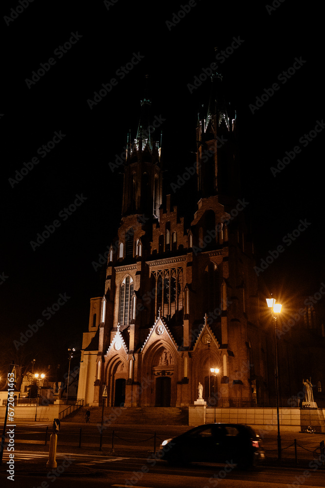 Roman Catholic cathedral, Gothic style architecture illuminated by night lanterns. Cathedral Basilica of the Assumption of the Blessed Virgin Mary. Białystok Cathedral, Bialystok, Poland 3 March 2021